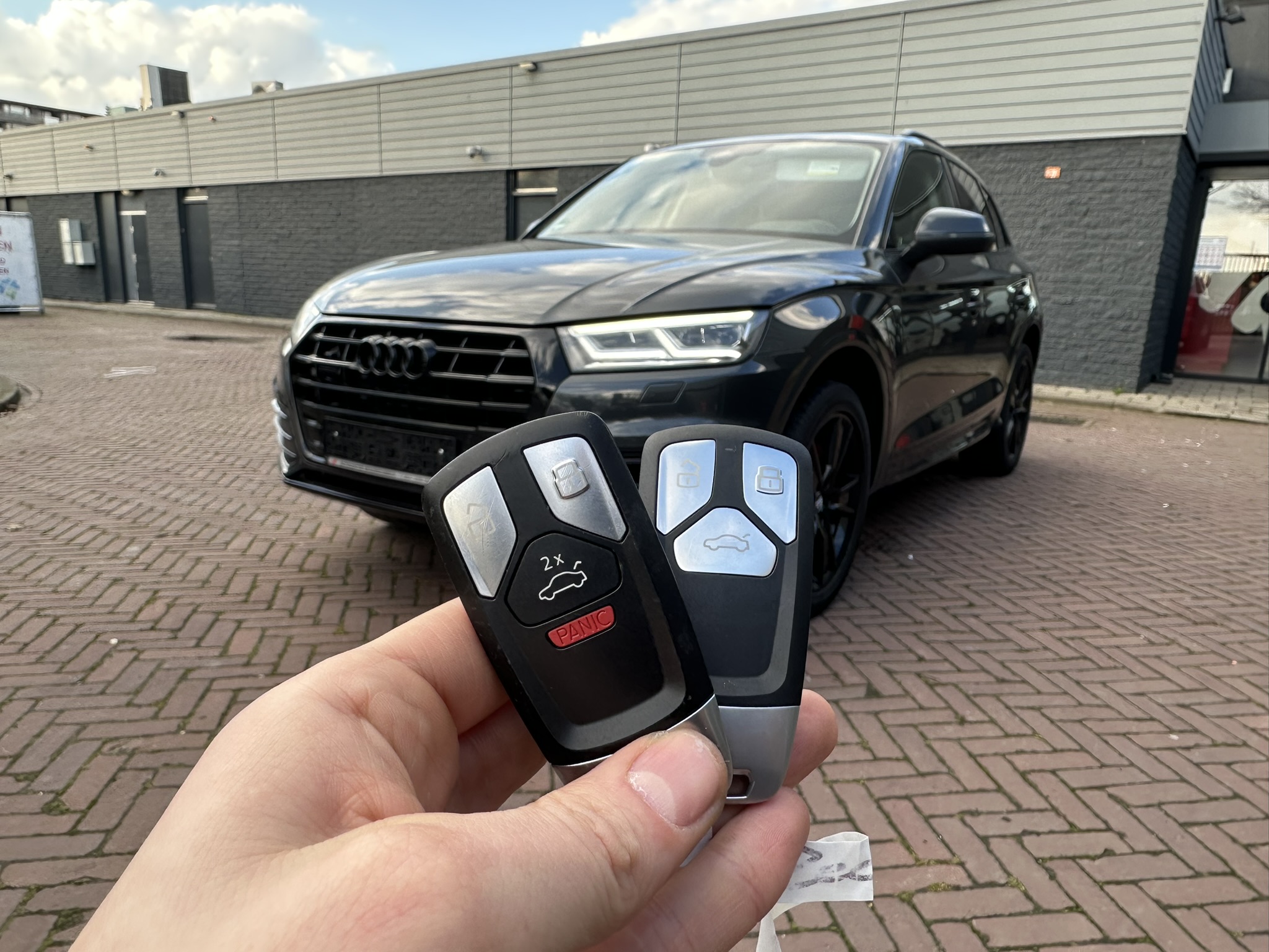 Nieuwe Audi-sleutel naast het origineel met rode PANIC-knop, voor een zwarte Audi SQ5